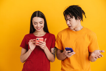 Young multiracial couple posing and using mobile phones