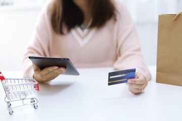 Woman spending money and Small shopping cart with internet banking on Laptop for Internet online e-commerce shopping working from home