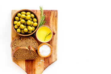 Olives in wooden bowls with sliced bread and oil, top view