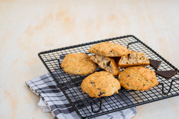 Homemade oatmeal cookies with banana and chocolate on a black wire rack on a light concrete background.