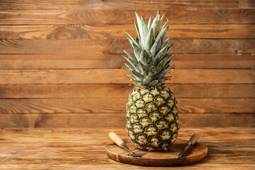 Plate with fresh pineapple and cutlery on wooden background