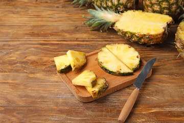 Board with cut fresh pineapple on wooden background