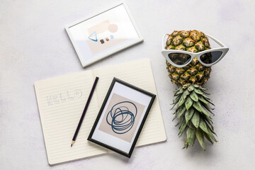 Pineapple with sunglasses, notebook and pictures on white background