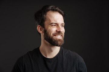 Bearded brunette white man smiling and looking aside