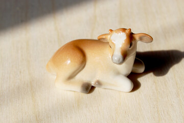 Cute photo of a porcelain cow figurine on a wooden background