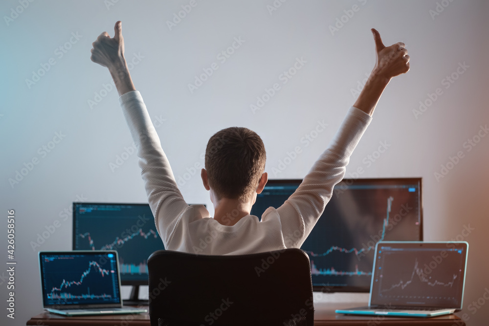 Wall mural successful male trader looking at monitor with stock exchange graph or chart