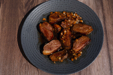 Duck breast fillet served on a black plate, fried with garlic, special asiatic soy sauce recipe.