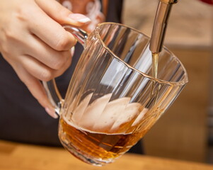 barman hands at beer tap pouring a draught lager beer serving in a restaurant or pub