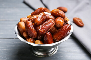 Bowl with sweet dried dates on dark wooden background, closeup
