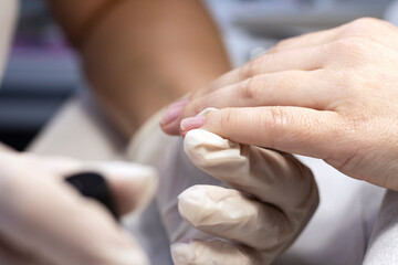 Manicure coating of nails on women's hands with gel polish in a beauty salon by a specialist. Close-up. Space for text