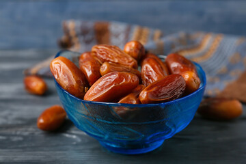 Bowl with sweet dried dates on color wooden background, closeup