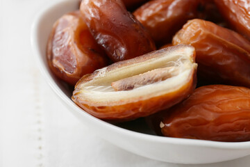 Bowl with sweet dried dates on light background, closeup