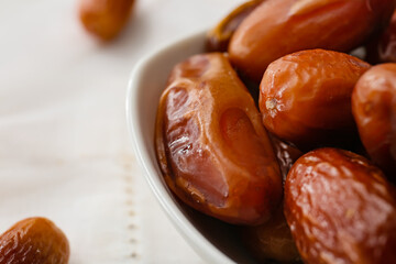 Bowl with sweet dried dates on light background, closeup
