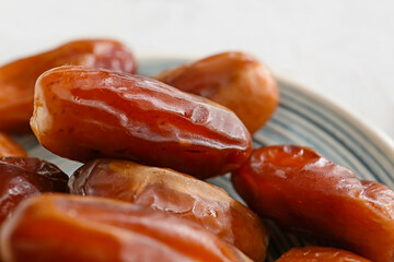 Plate with sweet dried dates on light background, closeup