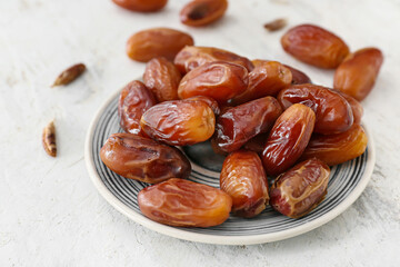 Plate with sweet dried dates on light background, closeup