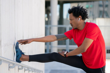 Afro athletic man stretching arms before exercise.