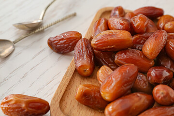 Board with sweet dried dates on light background, closeup