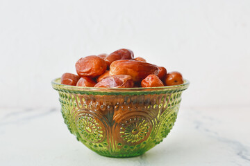 Bowl with sweet dried dates on light background, closeup
