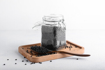 Jar of black lentils on light background