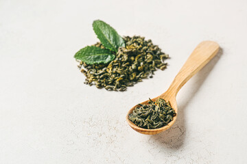 Fototapeta na wymiar Spoon with dry green tea on light background