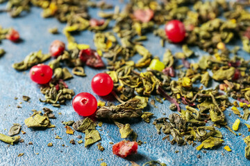 Dry green tea with red currant on color background