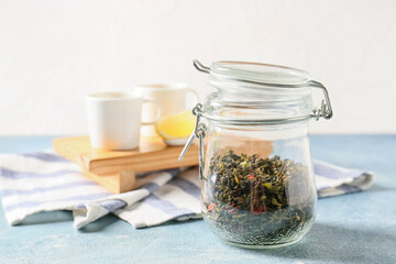 Jar of dry green tea on color background