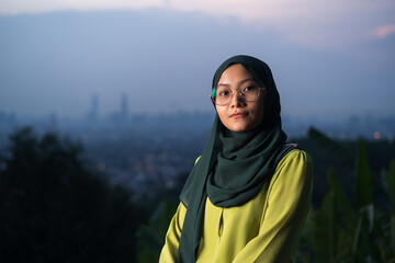 Portrait of young Asian woman during sunset, blue hour at hill view point, Bukit Ampang near Kuala Lumpur. Blurred background