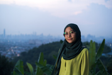 Portrait of young Asian woman during sunset, blue hour at hill view point, Bukit Ampang near Kuala Lumpur. Blurred background