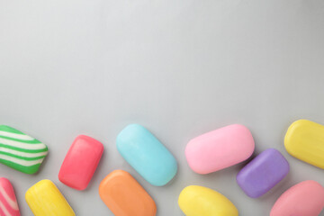 Different soaps in different soap dishes. A lot of solid soap for hygiene and cleanliness. Colorful soap and remnants are scattered on grey background.