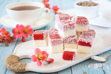 Homemade panna cotta and red fruits cubes in coconut flakes and cup ot tea, blooming japanese...