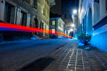 Long exposure shot of the old town of Fribourg, with colorful vehicle light trails in the foreground, shot in Fribourg, Switzerland
