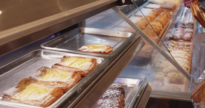 A woman makes purchases in a supermarket, a girl puts bread pastries in a bag with tongs, woman chooses cake in a supermarket.Grocery shopping concept.Selection of products in supermarket for cooking