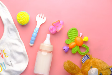 Toys for newborn baby set with teddy bear and milk in bottle on pink 