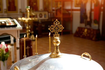 Orthodox cross in the sun on the lid of the bowl for the rite of infant baptism.