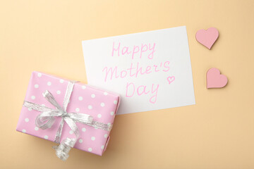 Mother's day card on beige background with a present. Happy Mother's day