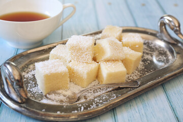Apple gelatin dessert. Sugar free. Homemade marshmallow cubes in coconut flakes and cup of tea