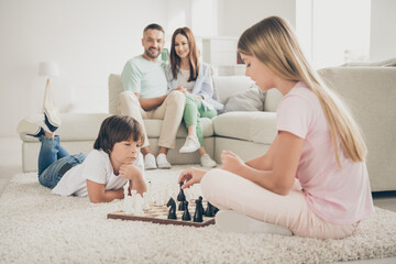 Photo portrait of friendly family spending time together little children daughter son playing chess near parents