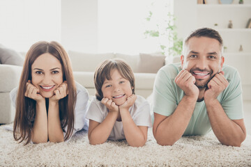 Photo of optimistic nice family mom dad kid hands face lie on floor wear t-shirts at home