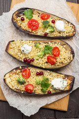 Halves of baked eggplant with bulgur and tomatoes on cutting board.