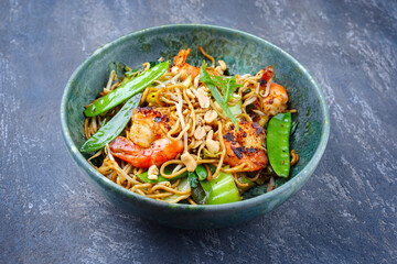 Modern style traditional Thai phak kung curry with barbecue king prawns and noodles as close-up in Nordic design bowl with copy space