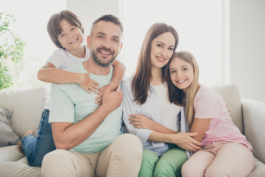 Photo portrait of happy children spending free time with parents embracing hugging on sofa in living room