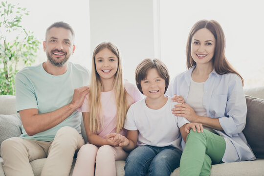 Photo of optimistic full family with two kids hug sit on sofa wear casual cloth t-shirts pants at home