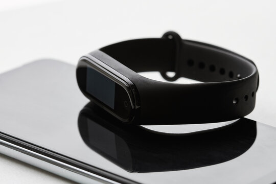 Black fitness watch or activity tracker. Fitness tracker lies on the smartphones. Closeup, selective focus