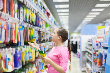 Teen girl in   stationery department at supermarket