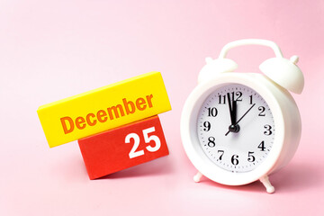 December 25th. Day 25 of month, Calendar date.White alarm clock on pastel pink background. Winter month, day of the year concept.
