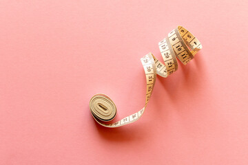 White measuring tape on a pink background. Close-up.