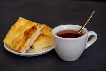 Tea in a white cup with a curd casserole on a saucer. Breakfast. Close-up. Selective focus.