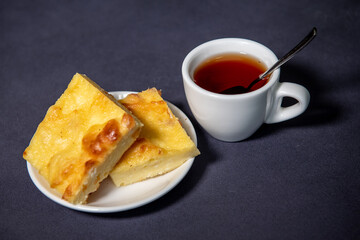 Tea in a white cup with a curd casserole on a saucer. Breakfast. Close-up. Selective focus.