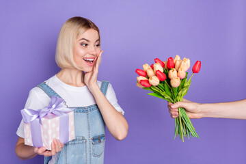 Photo of nice impressed short hairdo blond lady hold flowers present wear white t-shirt isolated on violet background