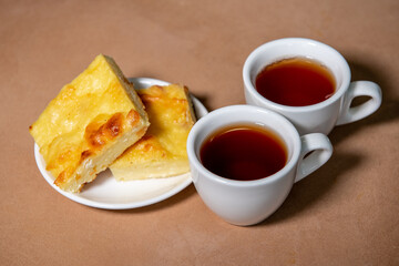 Two cups with tea, cottage cheese casserole on a saucer. Breakfast. Close-up. Selective focus.